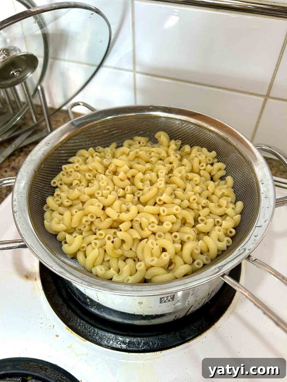 Creamy Classic Macaroni Salad Recipe for Picnics and Potlucks 4 cooked macaroni draining over pot.