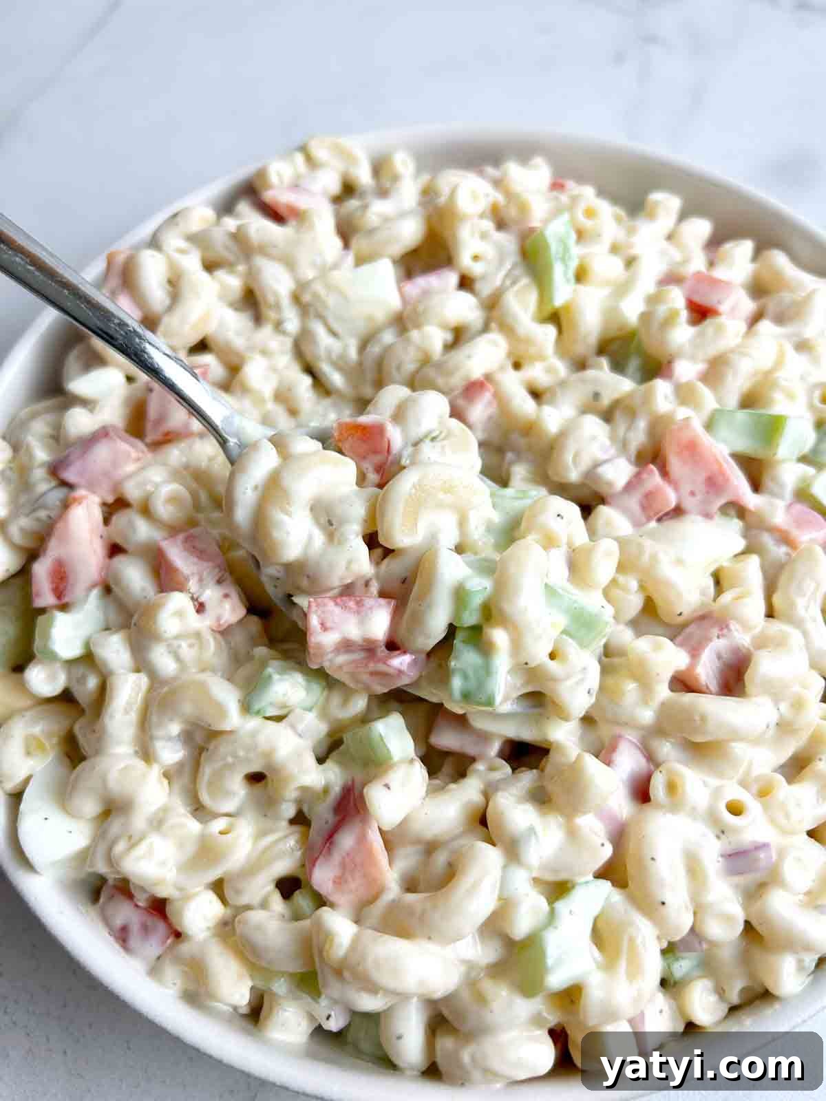Creamy Classic Macaroni Salad Recipe for Picnics and Potlucks 7 spoon lifting macaroni salad from bowl.