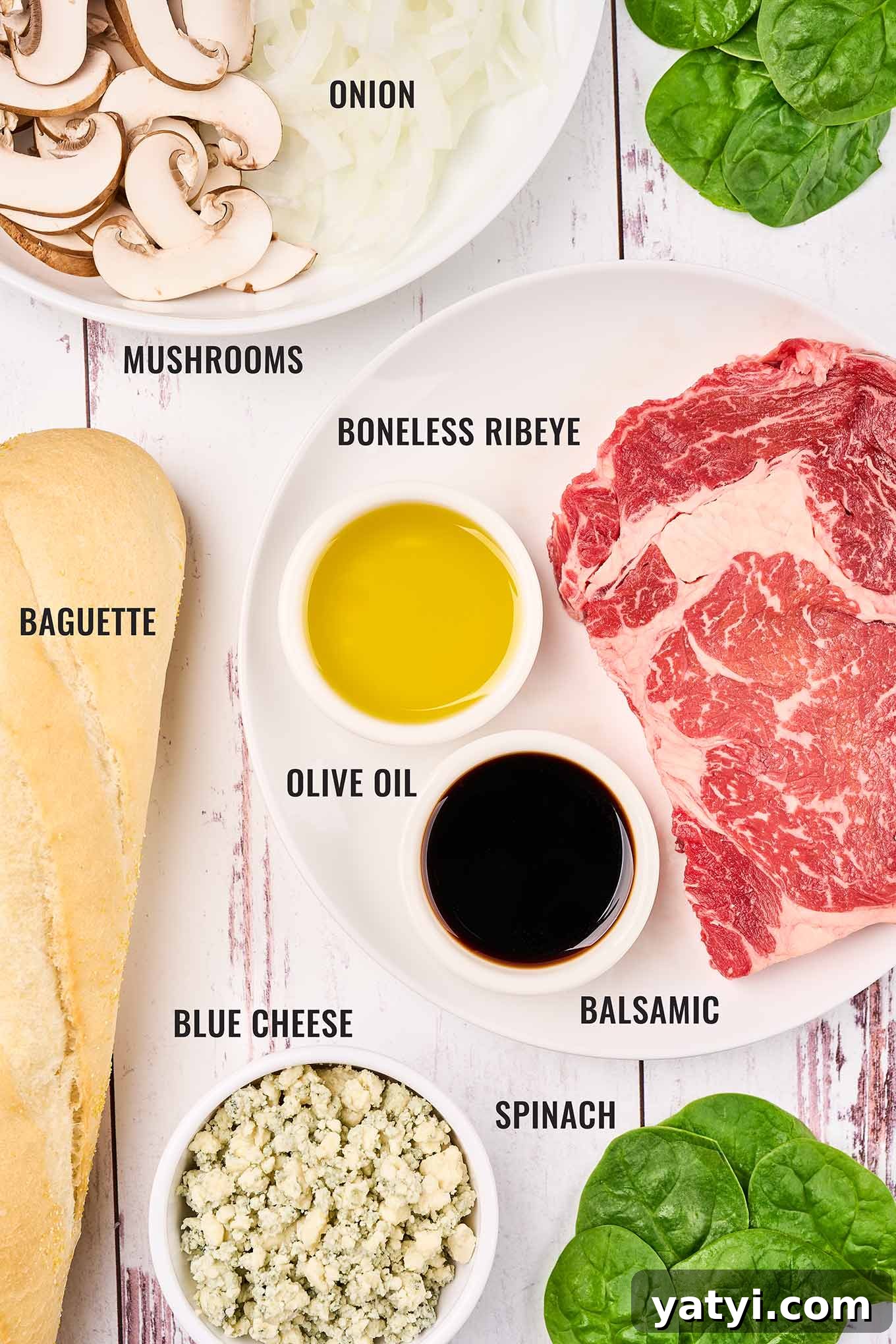 Ribeye Steak Sandwich with Creamy Blue Cheese Sauce 3 Labeled photos of ingredients to make a steak sandwich that includes boneless ribeye, onions, mushrooms, fresh spinach, blue cheese, and baguette.