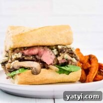 Ribeye Steak Sandwich with Creamy Blue Cheese Sauce 7 A grilled ribeye steak sandwich with sautéed onions, mushrooms, and blue cheese, sweet potatoes fries on the side.