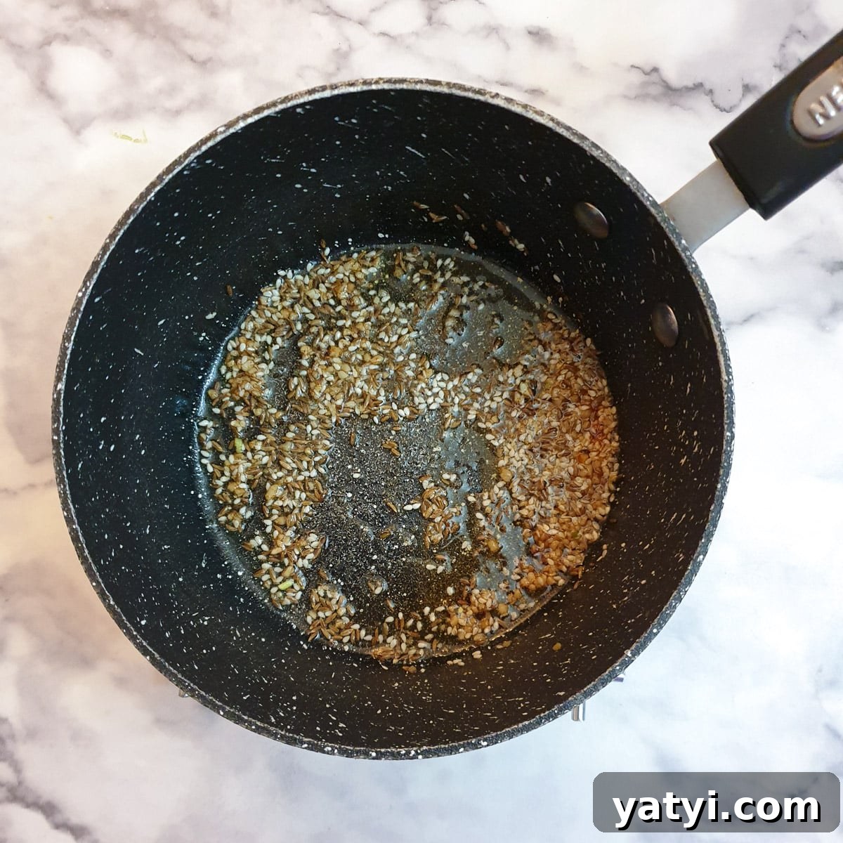 Crushed garlic, cumin and sesame seeds frying in ghee.