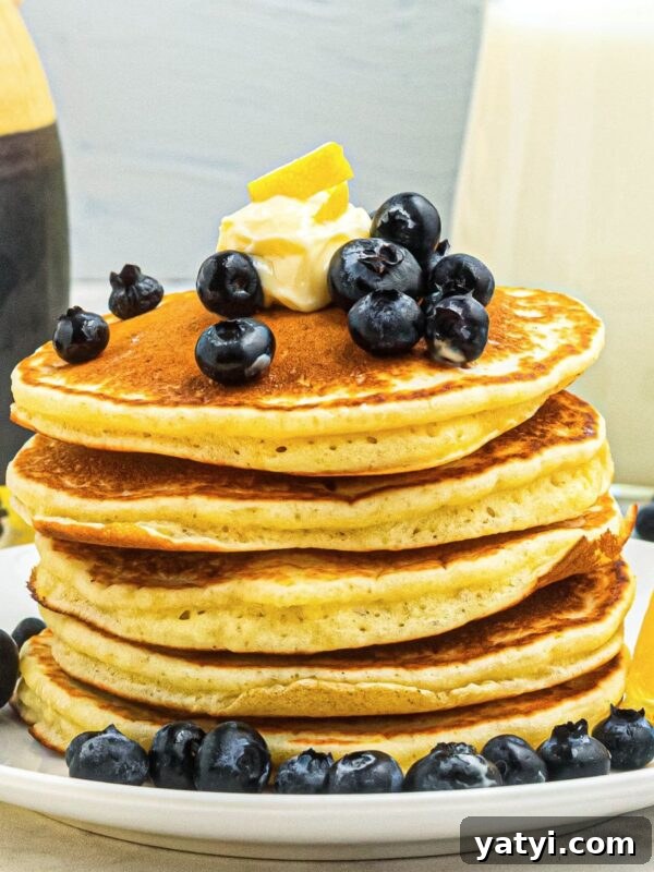 Classic Beanie Weenies Recipe: Hearty Sausage and Beans Meal 9 Golden fluffy pancakes stacked on a white plate, topped with blueberries and butter.
