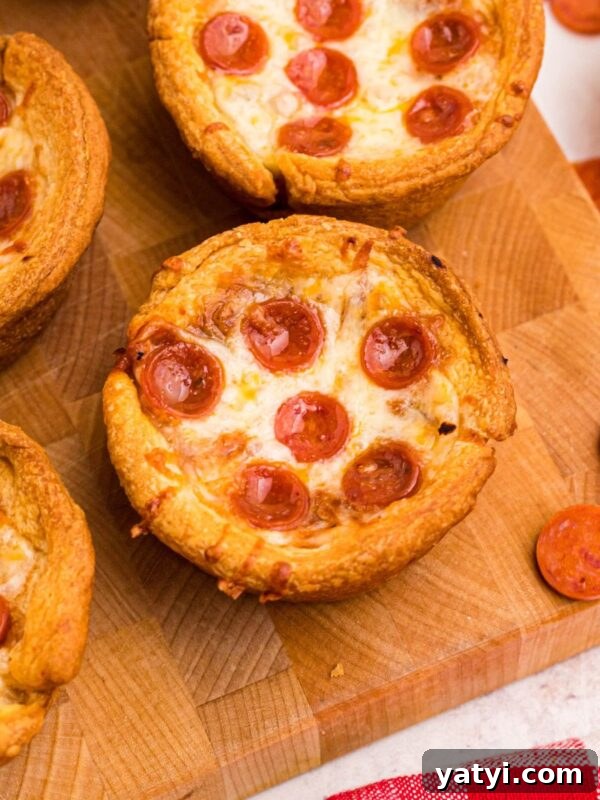 Classic Beanie Weenies Recipe: Hearty Sausage and Beans Meal 10 Golden crusted pizza cupcakes on a wooden cutting board with pepperoni scattered around the table.