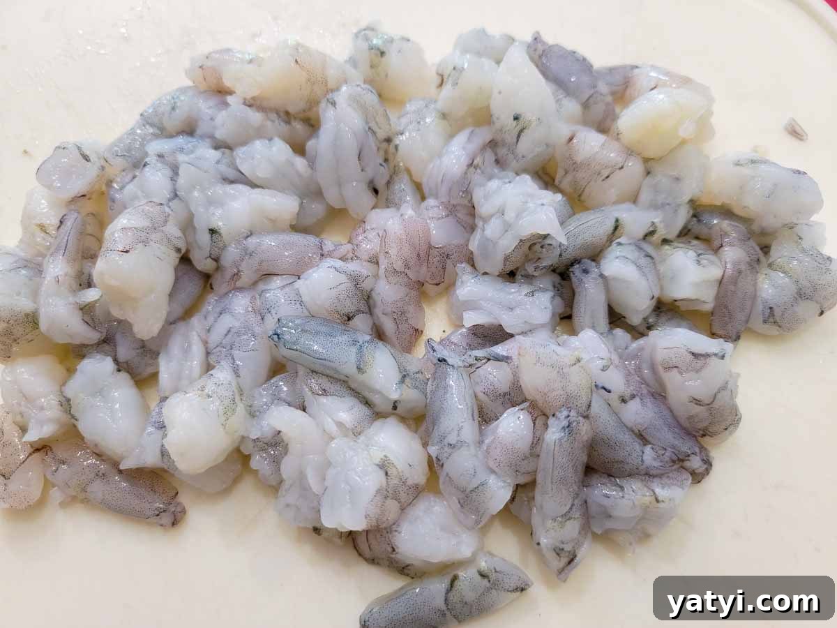 raw shrimp diced on a cutting board.