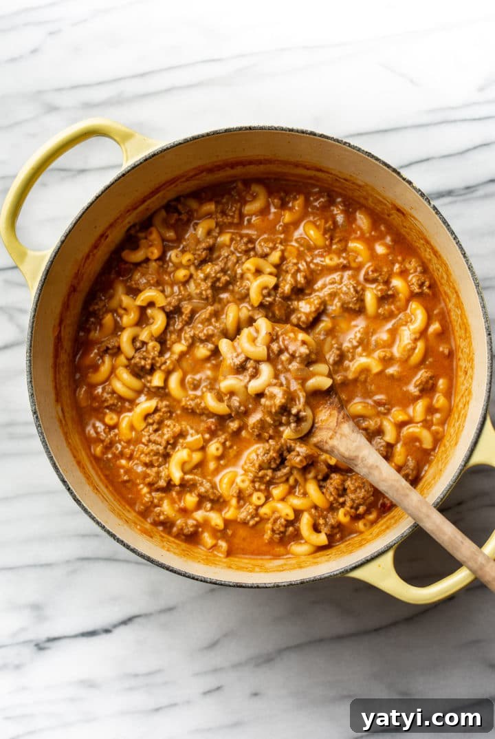 One-Pot Cheeseburger Macaroni Recipe for Quick Family Dinners 6 cheeseburger macaroni in a Dutch oven with a wooden spoon
