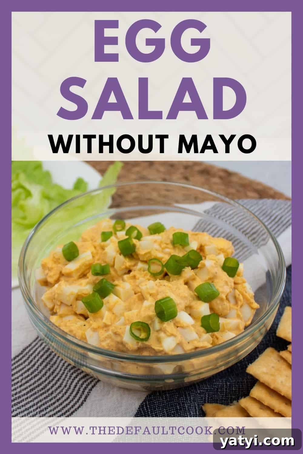 Creamy Egg Salad Without Mayo: Tangy Avocado & Yogurt Recipe 7 A bowl of egg salad topped with chopped green onions sits on a table next to crackers and lettuce. Text above reads Egg Salad Without Mayo. Website URL appears at the bottom.