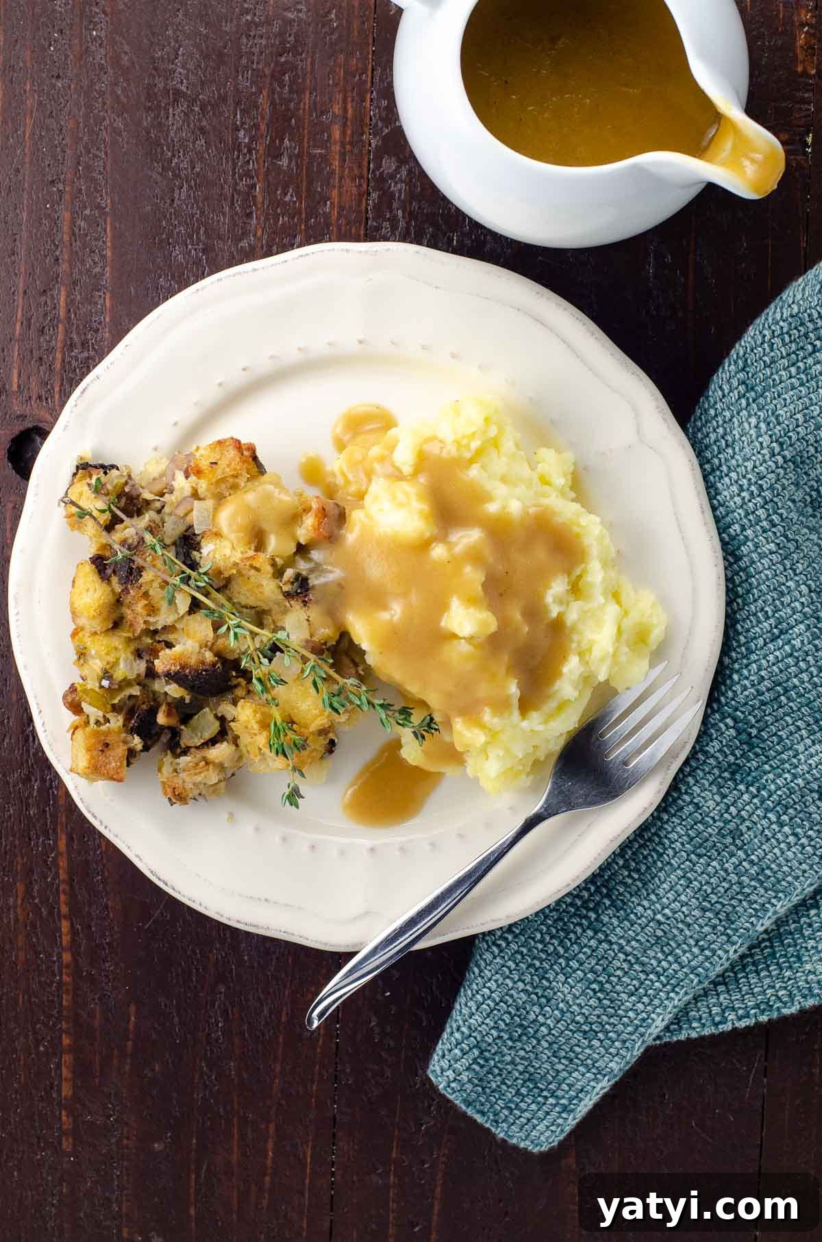 Vegan Thanksgiving Menu Ideas: Plant-Based Dishes to Impress 6 the best vegetarian gravy poured over mashed potatoes and stuffing on a plate with a fork and cloth napkin