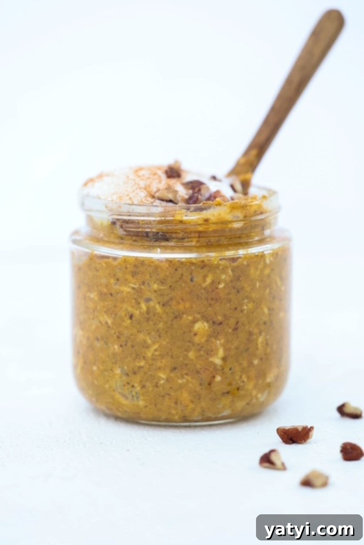 Creamy Pumpkin Overnight Oats Recipe for Fall Breakfast 2 Pumpkin Overnight Oats topped with whipped cream and chopped pecan pieces in a jar with a small wooden spoon.
