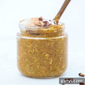Creamy Pumpkin Overnight Oats Recipe for Fall Breakfast 9 Pumpkin Spice Overnight Oats topped with whipped cream and chopped pecans in a jar with a small wooden spoon.
