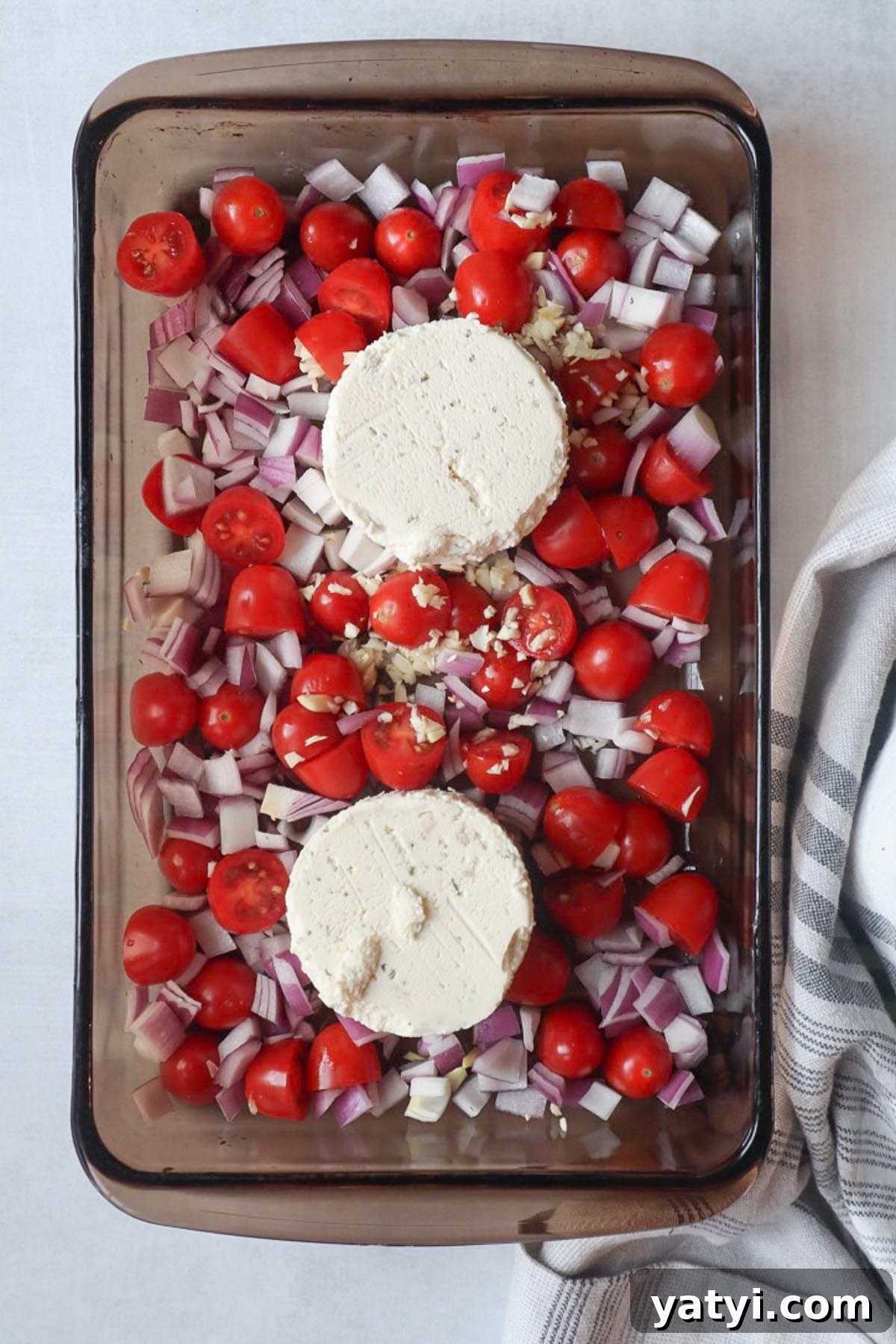 Creamy Boursin Tomato Pasta Bake — Viral TikTok Recipe 3 glass baking dish with tomatoes, red onion, garlic, and two Boursin pucks