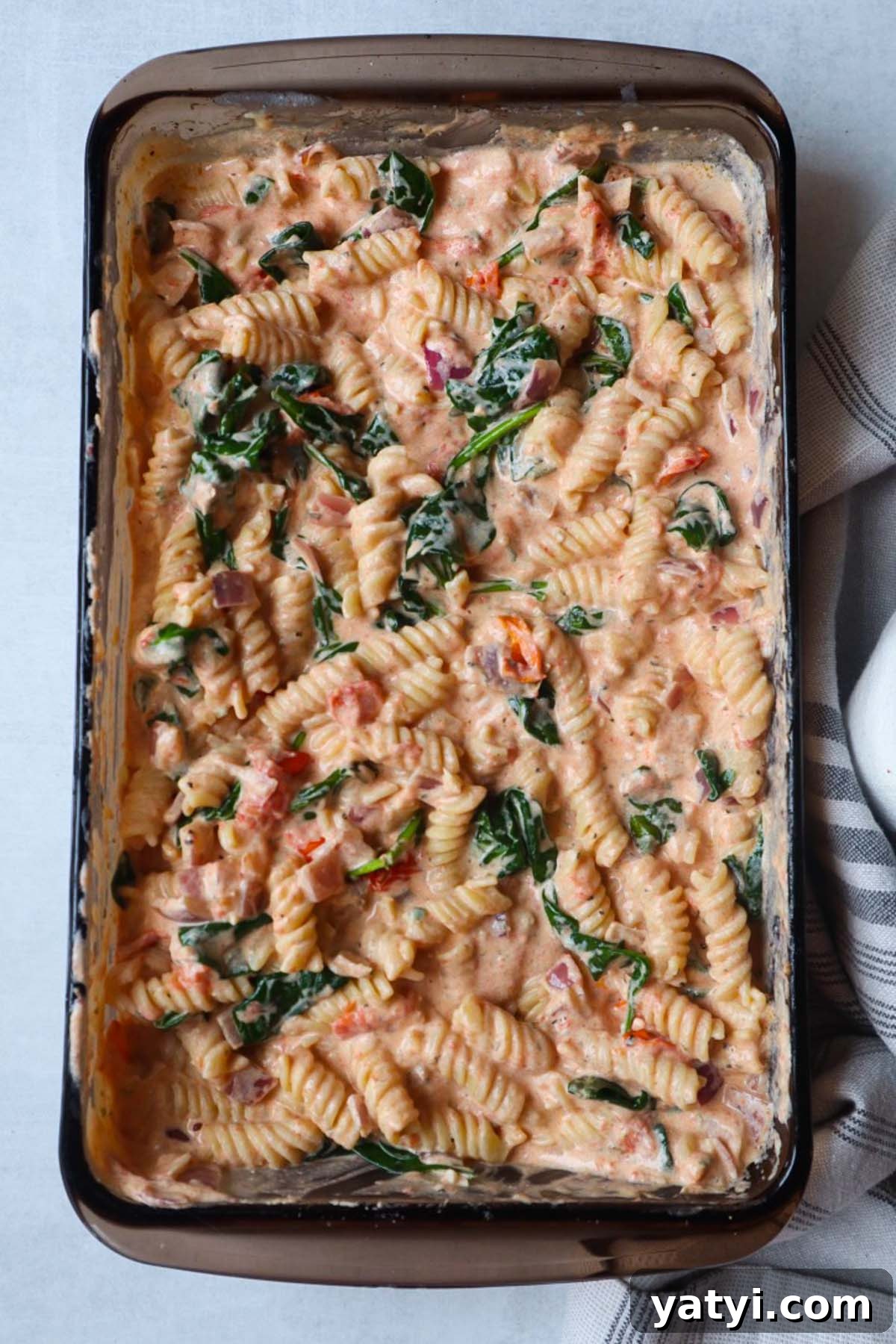 Creamy Boursin Tomato Pasta Bake — Viral TikTok Recipe 6 glass baking dish with rotini in a creamy boursin tomato sauce with spinach