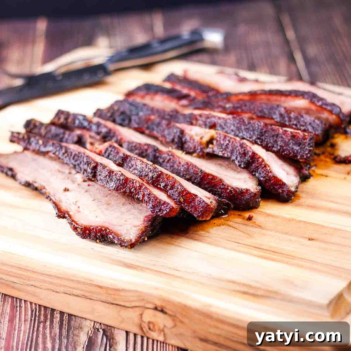The smoked brisket sliced in thin slices on a cutting board.