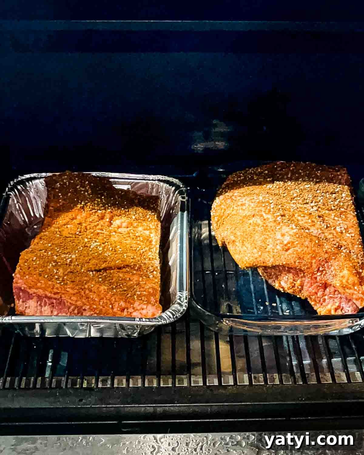 The brisket pieces in baking dishes placed on the pellet grill.