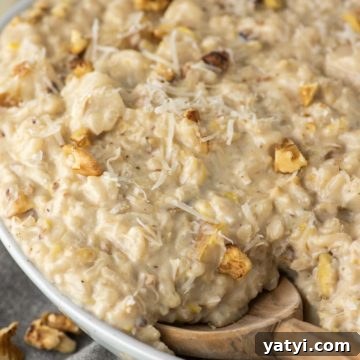 Wooden spoon dipped in bowl of pear risotto.