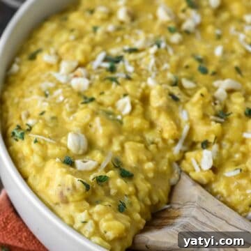 Creamy Chicken and Pumpkin Risotto Recipe for Fall Nights 15 Wooden spoon dipped in bowl of chicken and pumpkin risotto.
