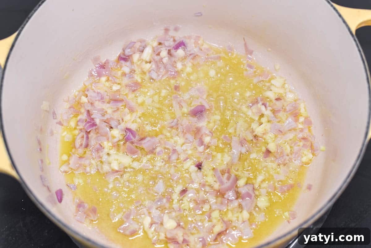 Creamy Chicken and Pumpkin Risotto Recipe for Fall Nights 4 Shallots and garlic being cooked in butter and oil in Dutch oven.