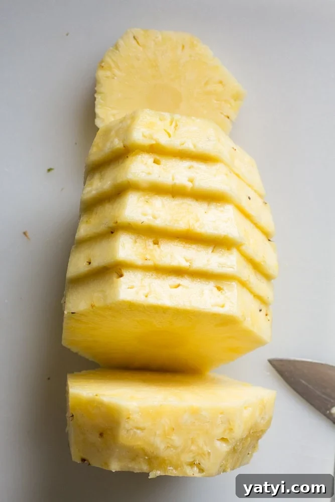 Juicy Grilled Pineapple Recipe — Naturally Sweet, No Added Sugar 6 Slices of pineapple on a white cutting board.