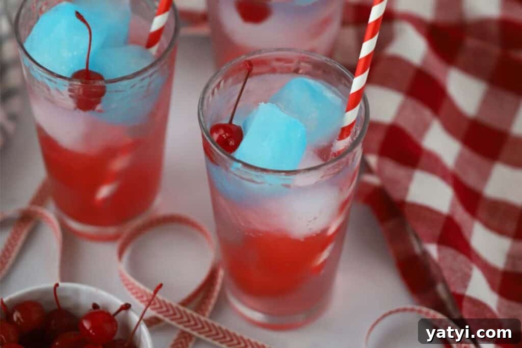 Refreshing Patriotic Punch Recipe for Summer Gatherings 3 Two glasses with red white and blue 4th of july drinks made with colorful ice cubes of gatorade and maraschino cherries.