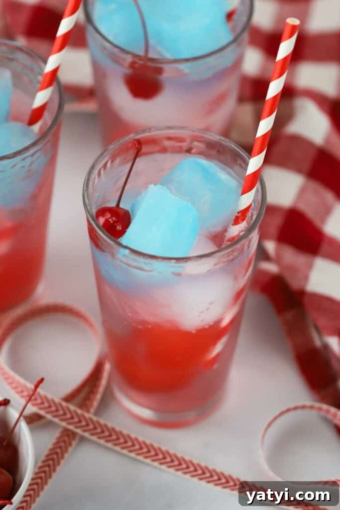 Refreshing Patriotic Punch Recipe for Summer Gatherings 5 A tall glass full of Sprite with red white and blue gatorade ice cubes and a colorful straw.