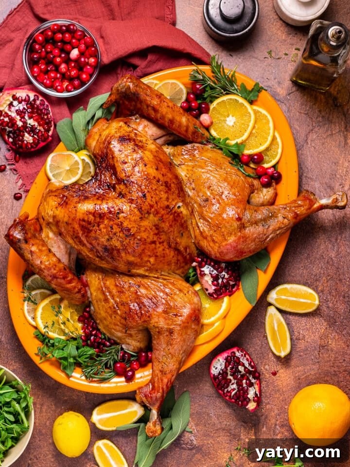 Dry-Brined Spatchcock Turkey: Complete Guide to Spatchcocking a Turkey 2 large orange platter with a roasted spatchcocked turkey. Garnished with rosemary, thyme, oranges, cranberries, pomegranate, arugula and sage.
