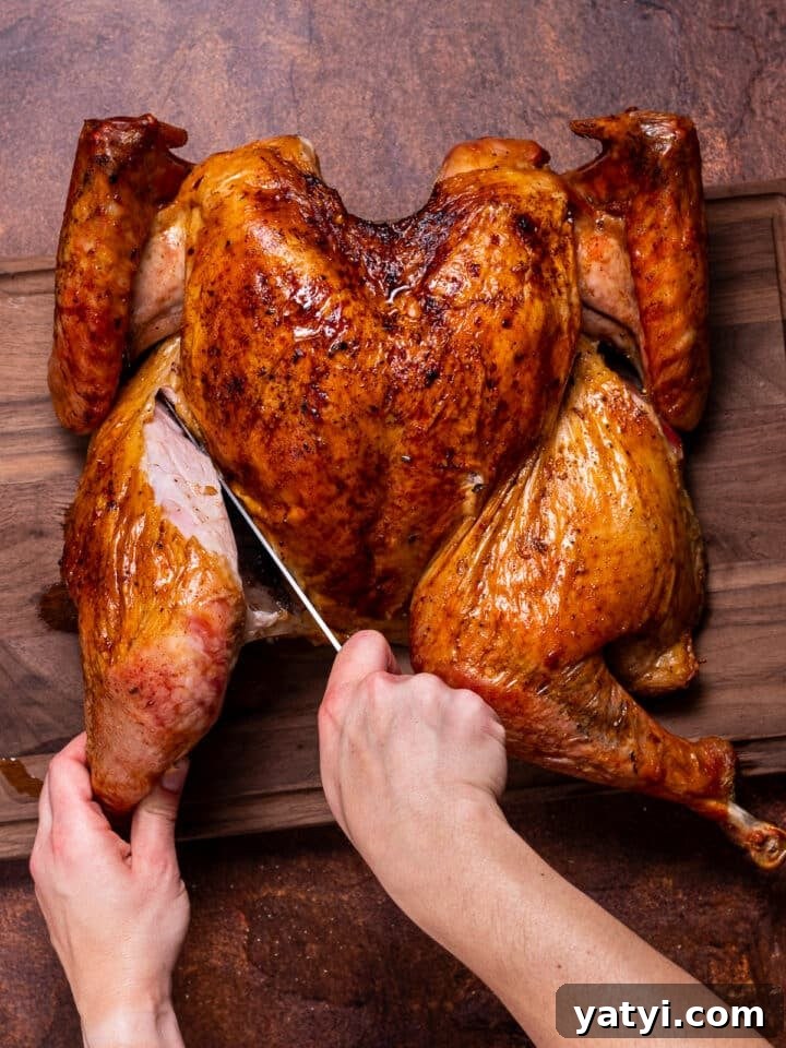 Dry-Brined Spatchcock Turkey: Complete Guide to Spatchcocking a Turkey 19 hands using a sharp chef's knife to remove turkey thigh from its body