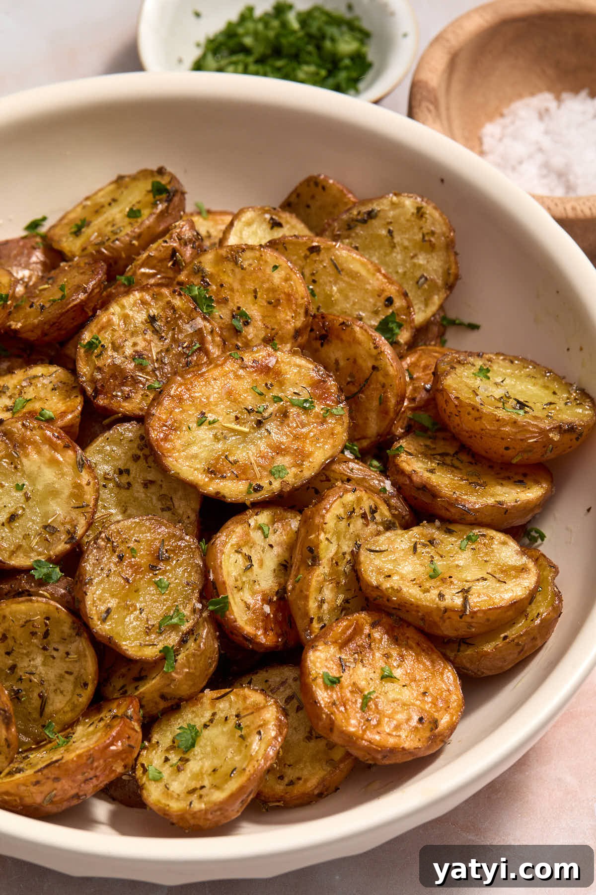 Crispy Air Fryer Baby Potatoes — 4 Ingredients Only 2 Close up of air fried baby potatoes with parsley and salt in the background.