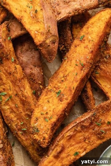 Close up view of air fryer sweet potato wedges arranged on brown parchment paper.