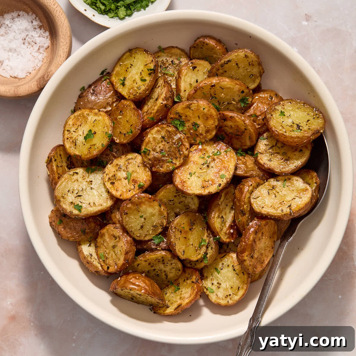Crispy Air Fryer Baby Potatoes — 4 Ingredients Only 14 Air fryer baby potatoes served in a white bowl and topped with sea salt and chopped fresh parsley.