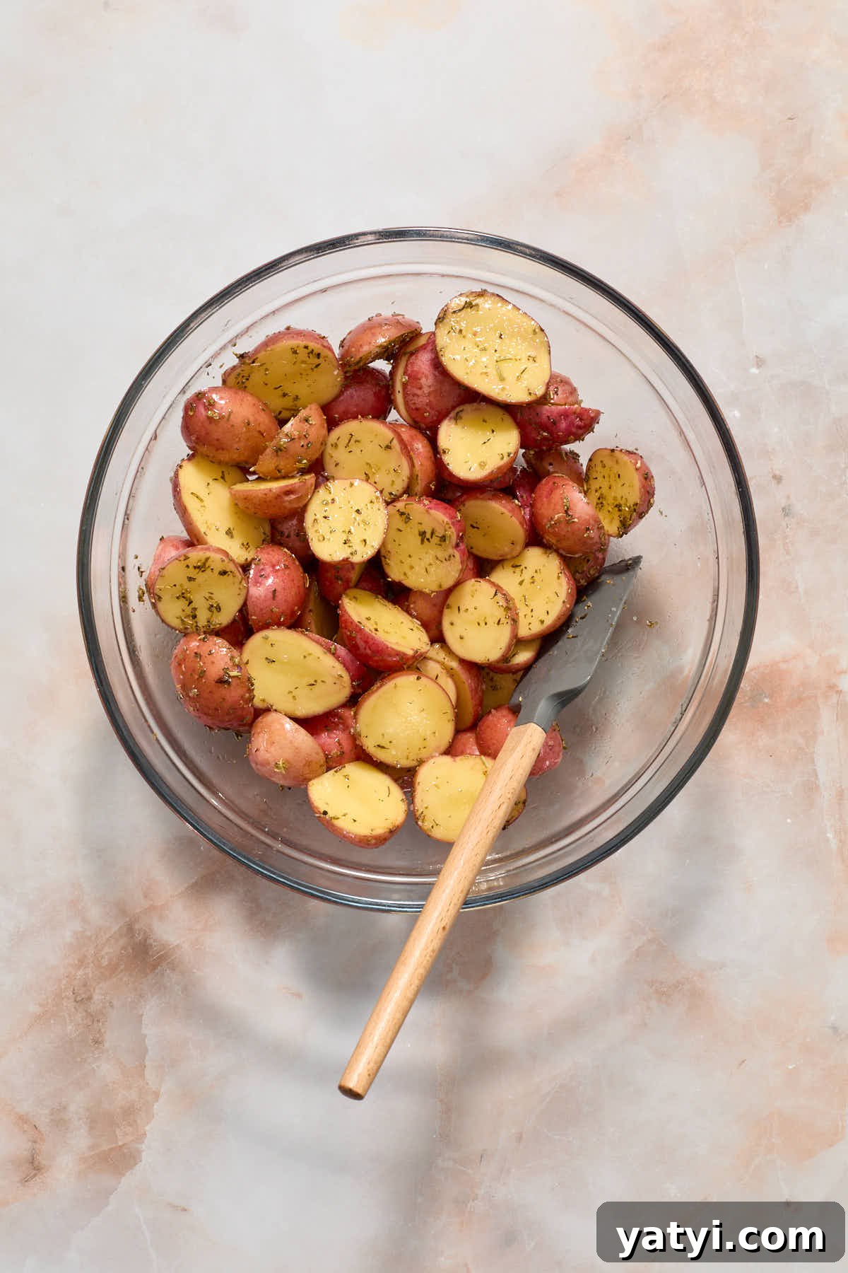Crispy Air Fryer Baby Potatoes — 4 Ingredients Only 5 Seasoned potatoes mixed together in a bowl with a spatula.