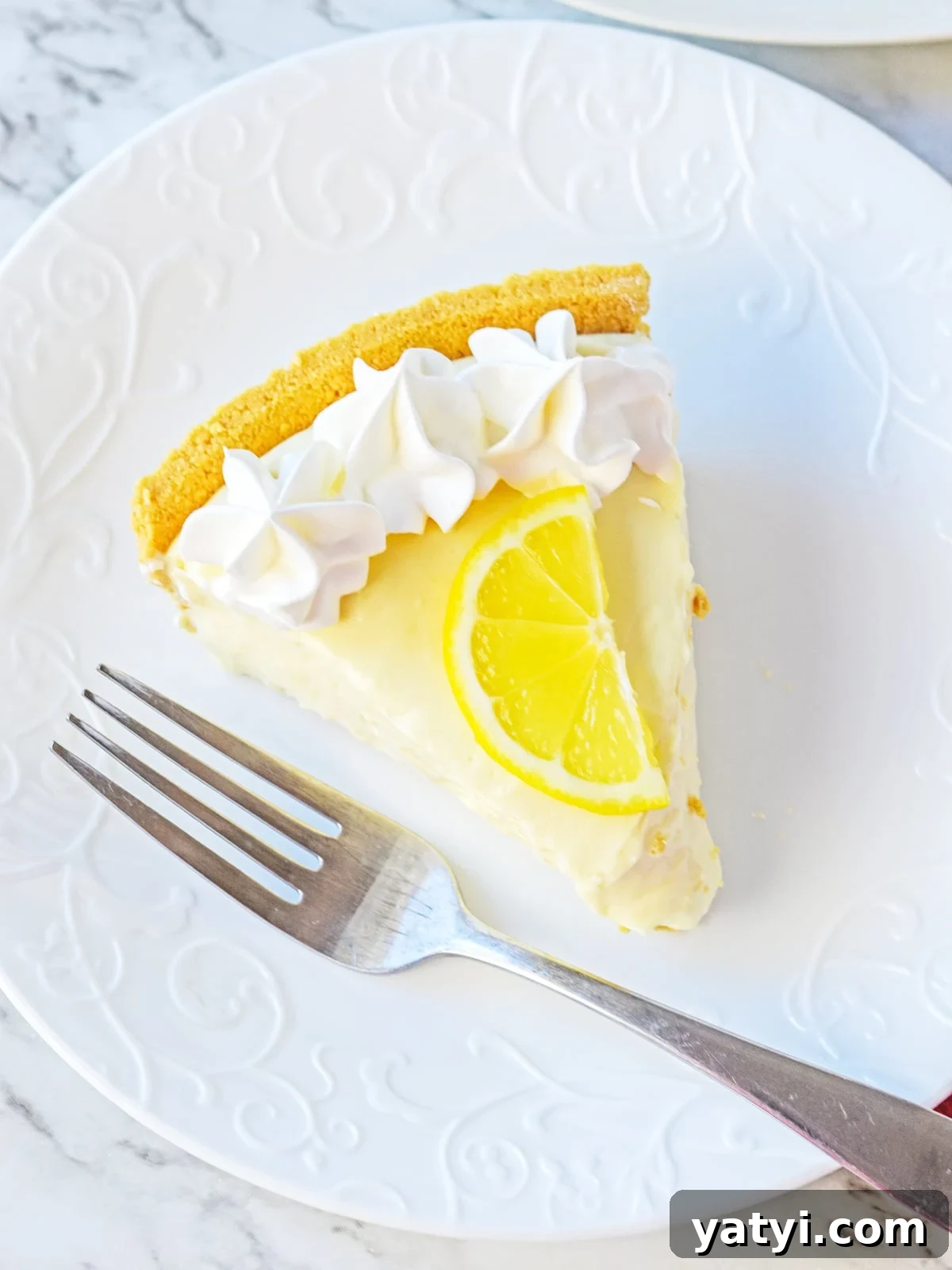 Zesty Lemon Pie with Graham Cracker Crust Recipe 7 lemon pie slice on a white plate with fork