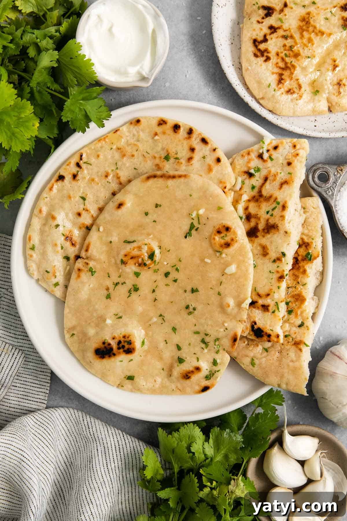 3 pieces of naan on a plate with 1 torn in half to show inside.