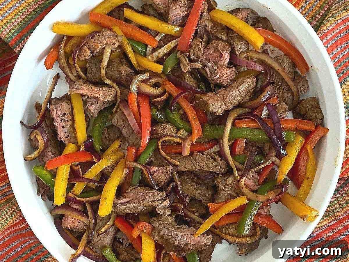 10 Quick Weeknight Dinners to Save Your Evenings 4 White platter with steak fajitas, onion with red, yellow, and green peppers.