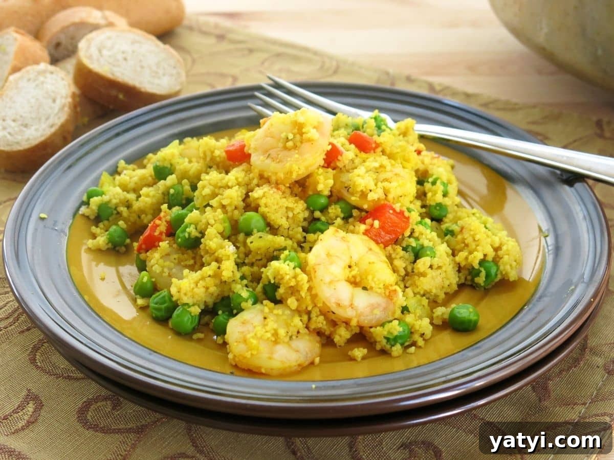 10 Quick Weeknight Dinners to Save Your Evenings 7 Shrimp couscous paella on a plate with a fork and slices of a baguette behind it.