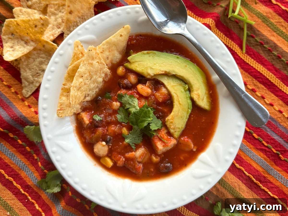 10 Quick Weeknight Dinners to Save Your Evenings 9 Chicken tortilla soup in a white bowl with a spoon topped with avocado slices and tortilla chips.