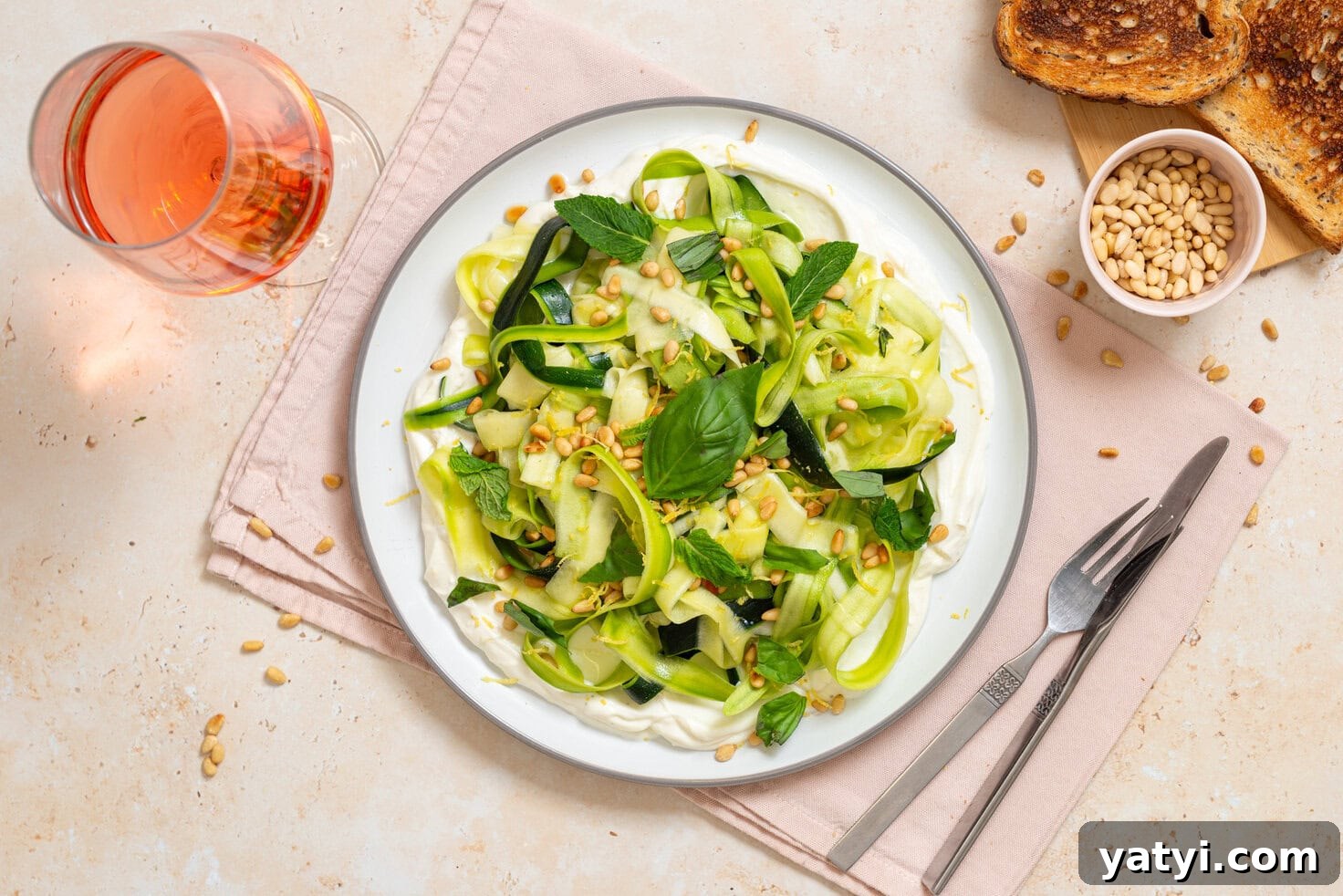 Zucchini Ribbon Salad with Whipped Lemon Ricotta Dressing 11 Zucchini ribbon salad over whipped lemon ricotta topped with basil, mint, toasted pine nuts, olive oil, and lemon zest on a white plate with toast and rosé nearby.
