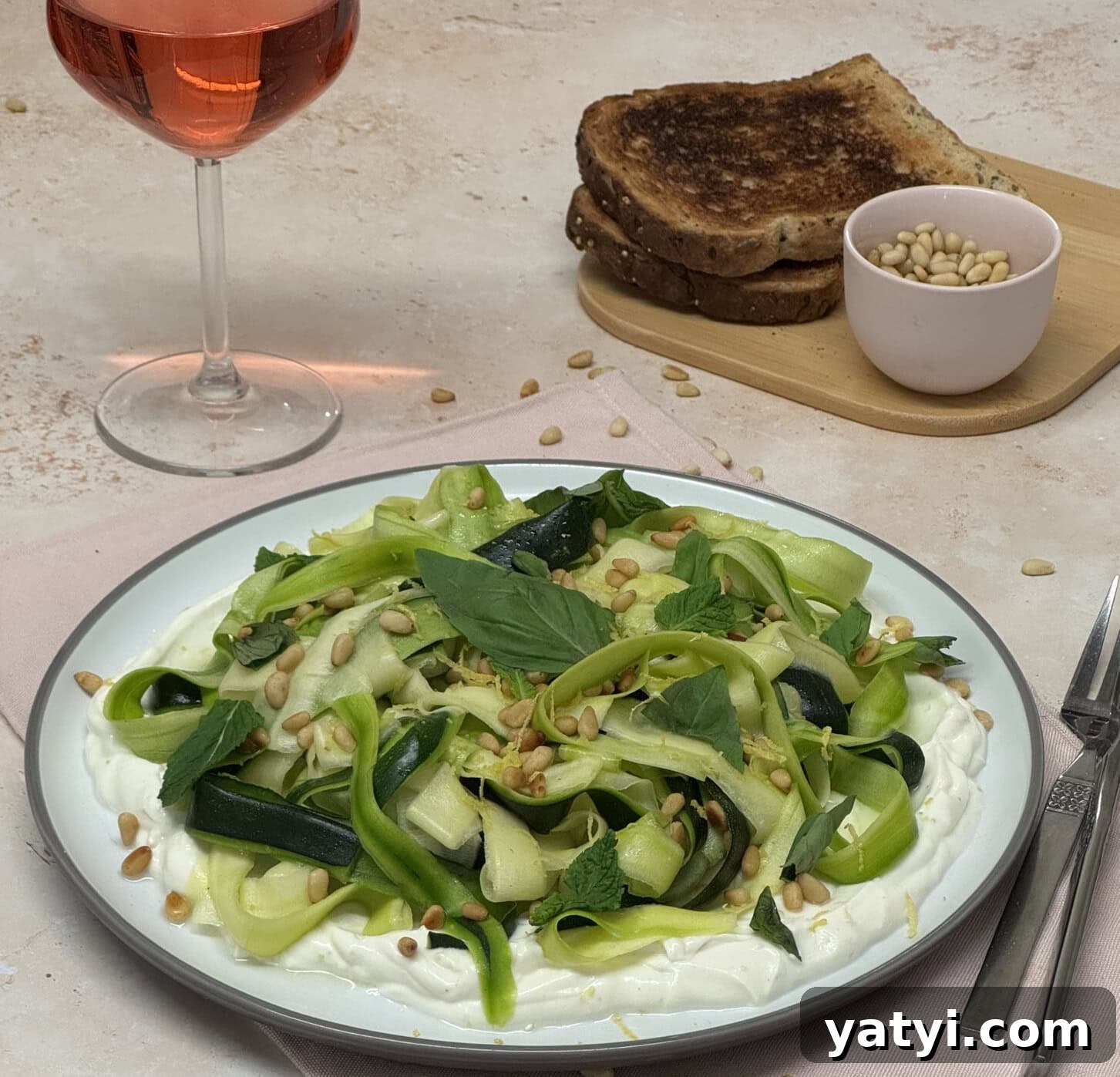 Zucchini Ribbon Salad with Whipped Lemon Ricotta Dressing 4 No-cook zucchini ribbon salad with whipped lemon ricotta, basil, mint, toasted pine nuts, and lemon zest served on a white plate.