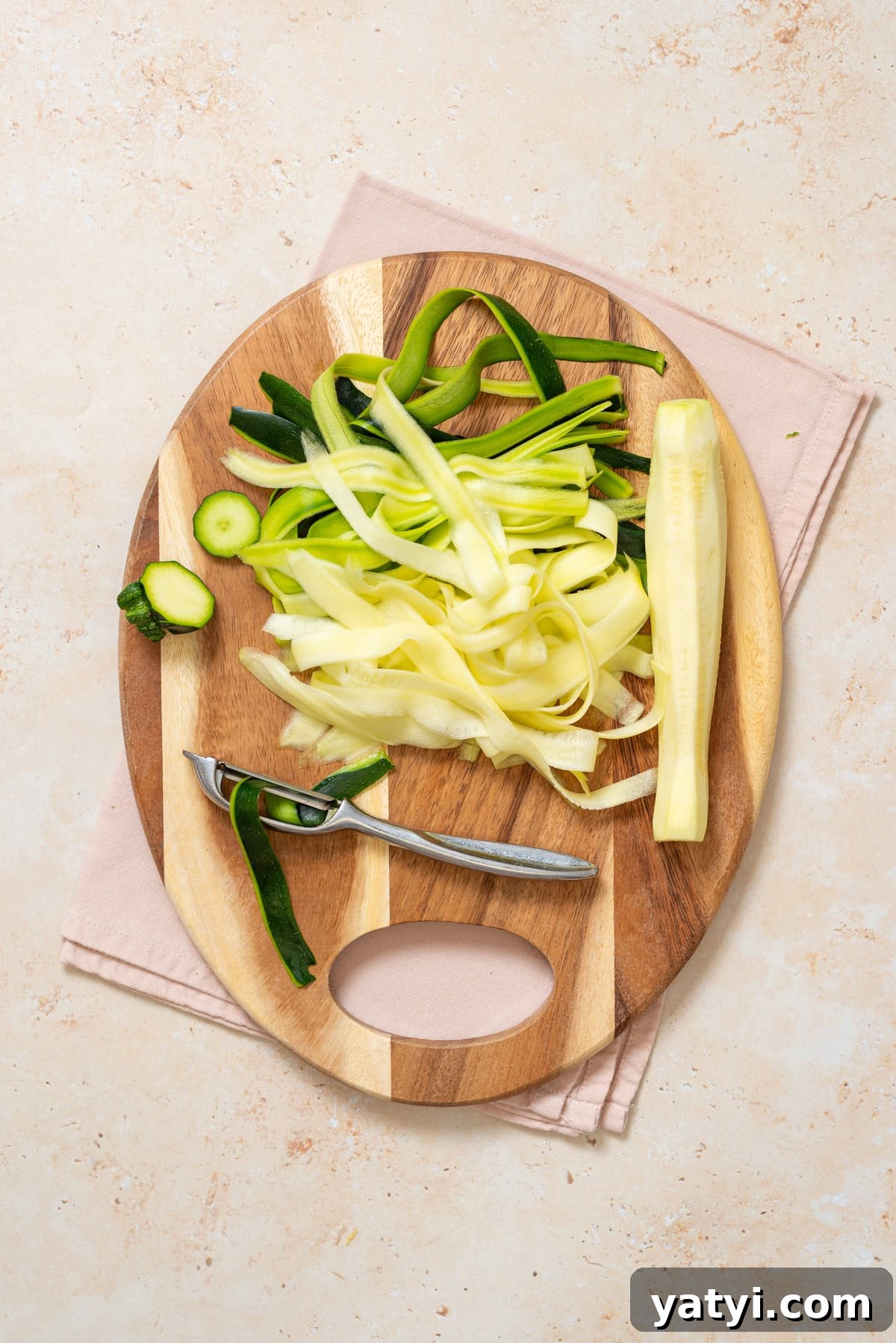 Zucchini Ribbon Salad with Whipped Lemon Ricotta Dressing 8 Shaving zucchini into long ribbons with a Y-peeler on a wooden cutting board.