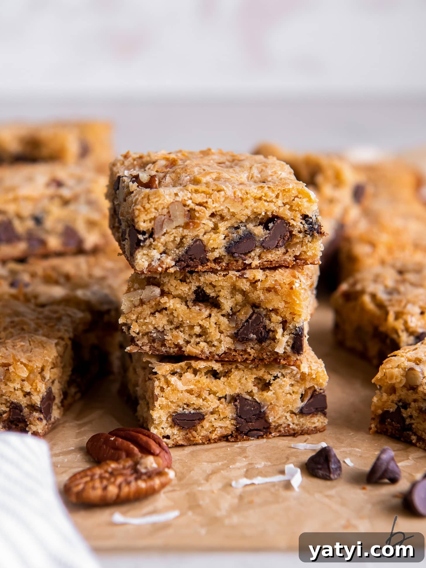 Coconut Congo Bars: Chewy Chocolate Chip Coconut Squares 5 stack of three congo bars showing coconut, pecans and chocolate chips inside.