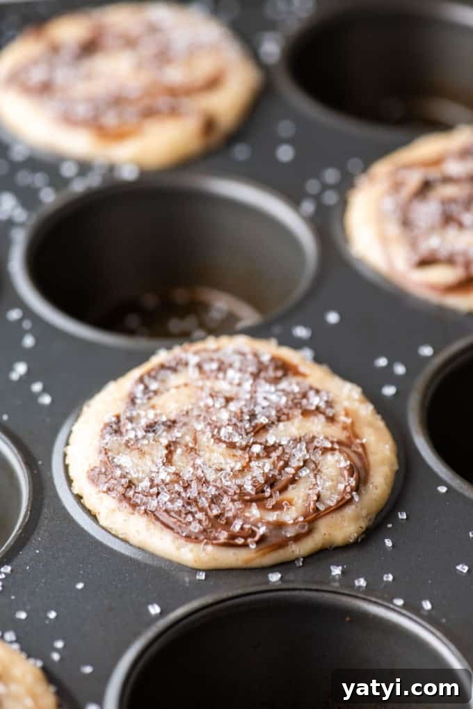 Nutella Swirl Muffins Recipe: Moist Chocolate-Hazelnut Muffins 11 a muffin pan with the batter for nutella swirl muffins in every other muffin hole, topped with sanding sugar