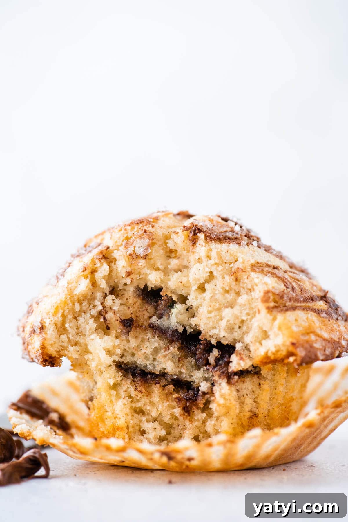Nutella Swirl Muffins Recipe: Moist Chocolate-Hazelnut Muffins 14 a nutella swirl muffin on top of an open muffin liner with a bite missing, exposing the nutella layers inside