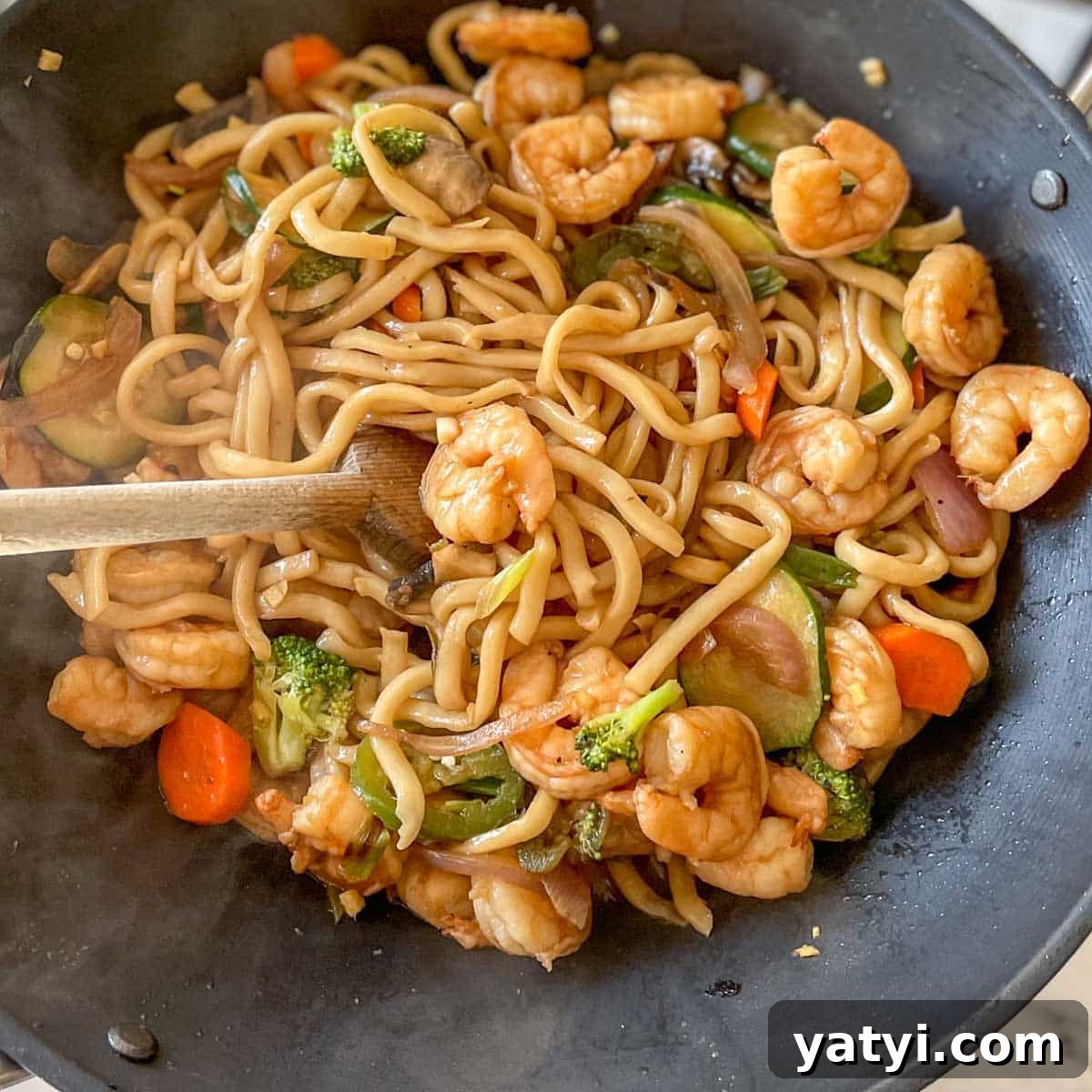 Shrimp is added back into the wok with noodles and vegetables.