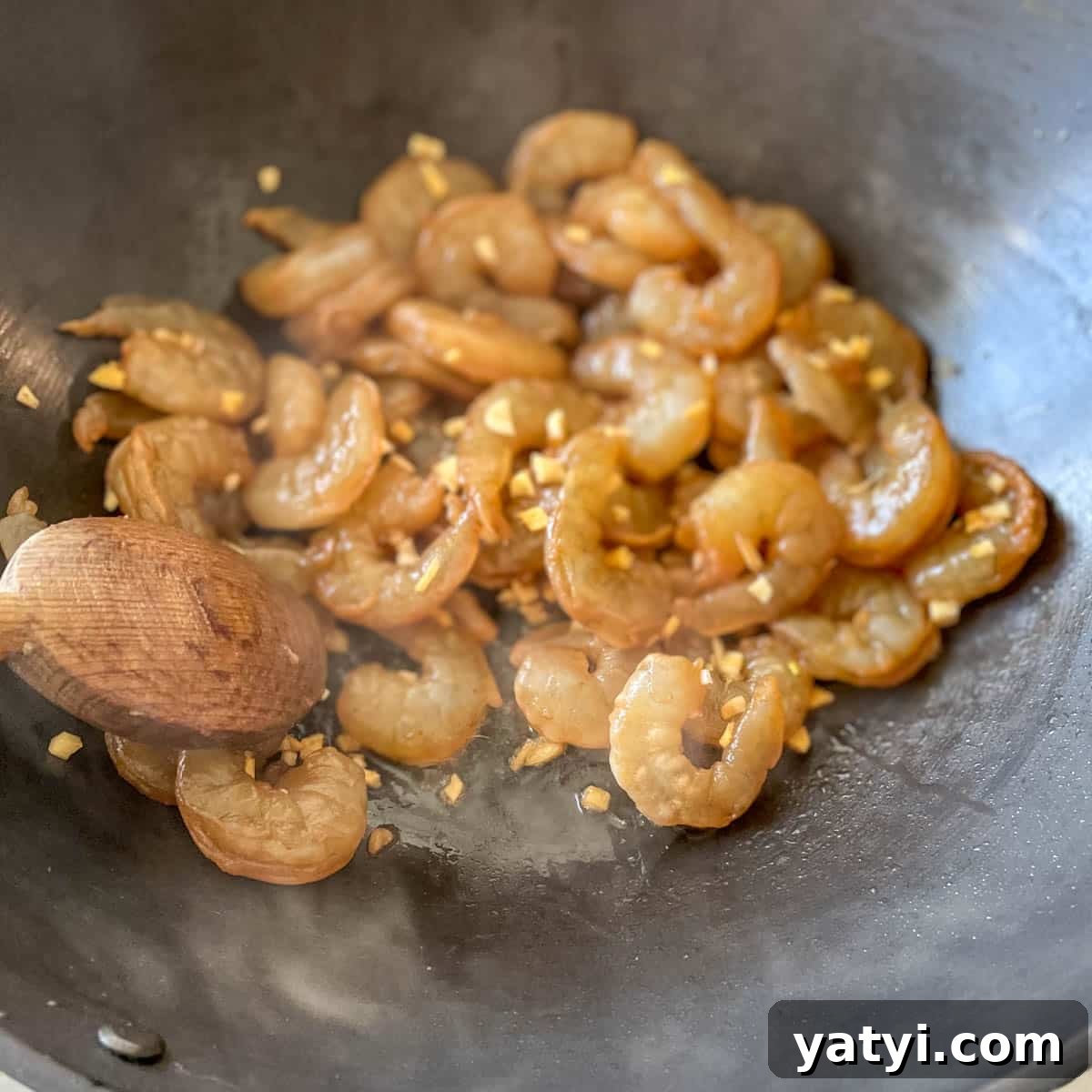 Marinated shrimp is cooked in a wok.
