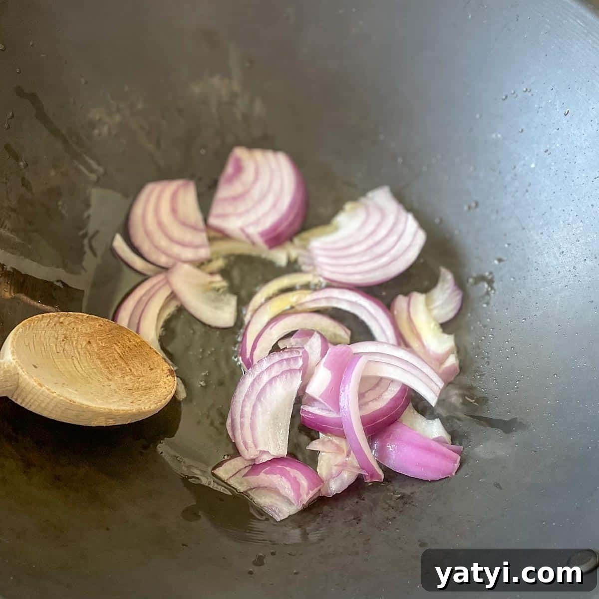 Onion is cooked in a wok.