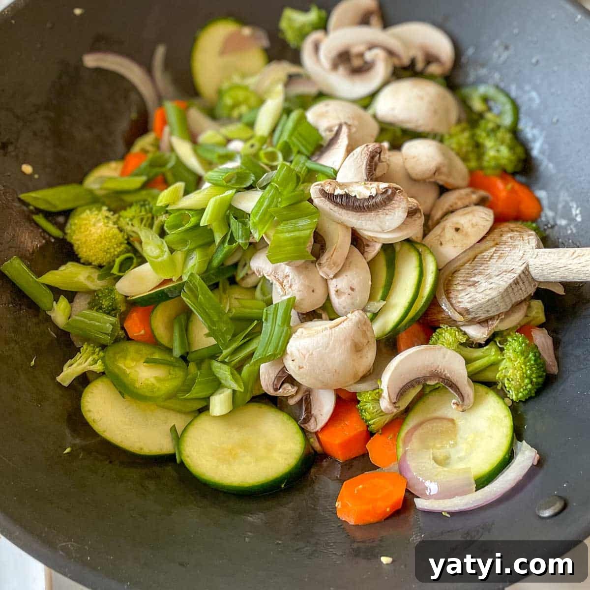 Mushrooms and scallions are added to the wok.