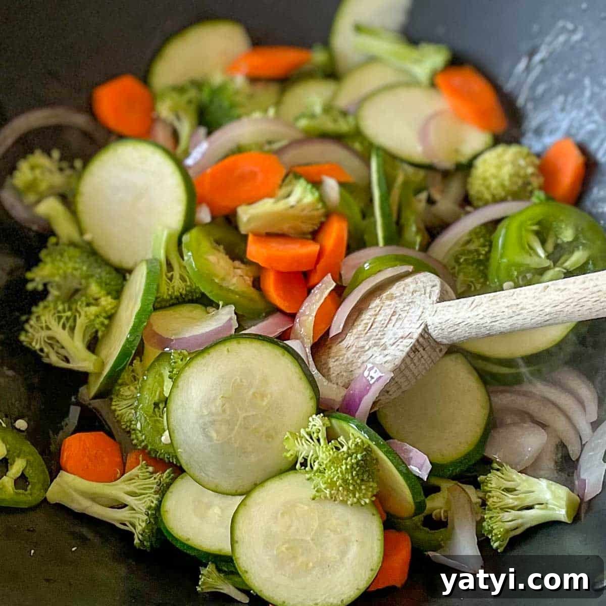 Zucchini, carrot, broccoli and jalapeño are added to the wok.