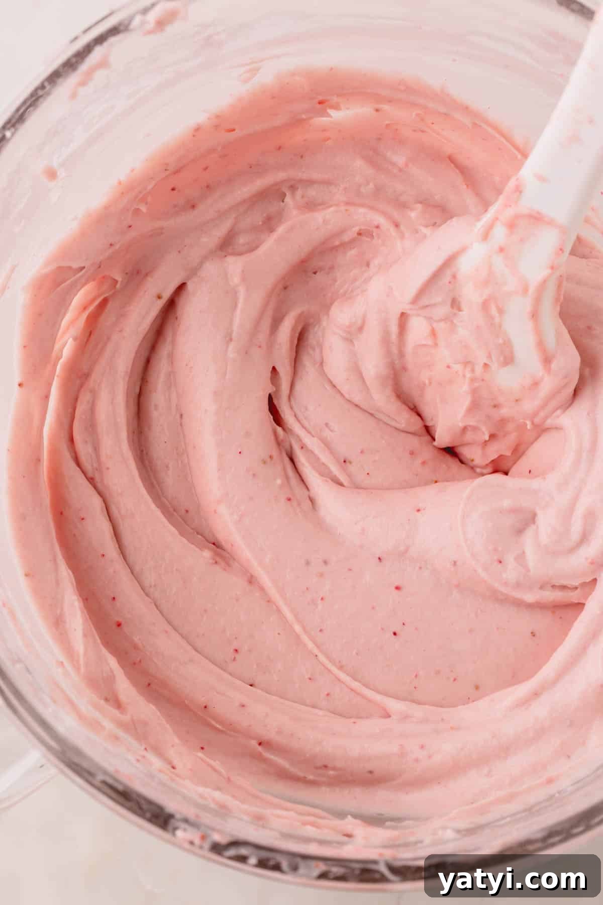Moist Homemade Strawberry Layer Cake Recipe 7 A bowl of strawberry cream cheese frosting with a spatula sticking out.