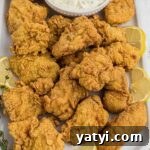 Crispy Southern Fried Catfish Nuggets with Tangy Dipping Sauce 14 A large platter of fried catfish nuggets with some lemon wedges and a tartar sauce.