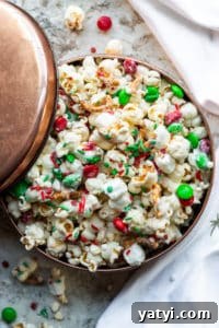 Christmas Crunch Popcorn Snack Mix Overhead shot of Christmas Crunch mix in a copper tin on a white counter with napkin.
