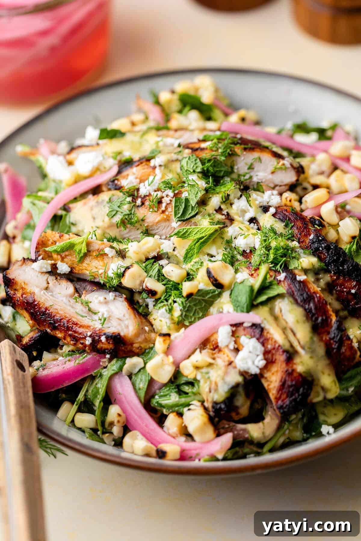 Grilled chicken salad with corn, pickled red onions, herbs, and cheese on a plate