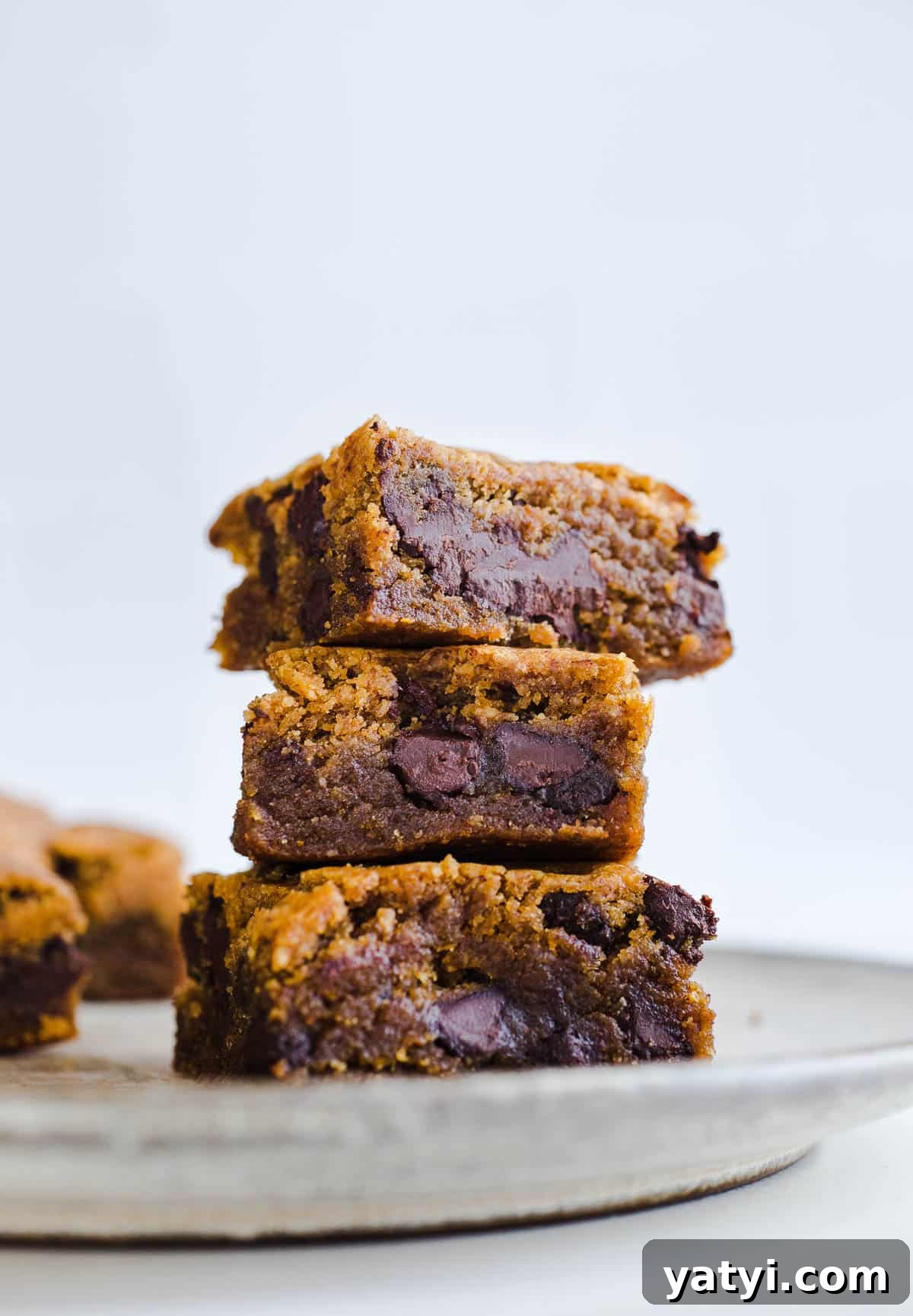 Gluten-Free Pumpkin Chocolate Chip Blondies You’ll Love 8 Chocolate chip blondies stacked on a plate.